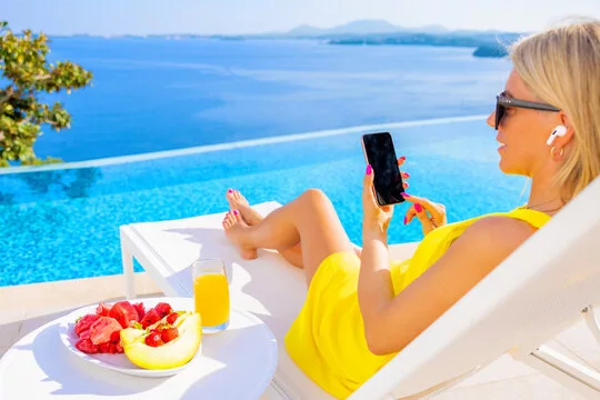 Woman with earbuds using cellphone by the pool