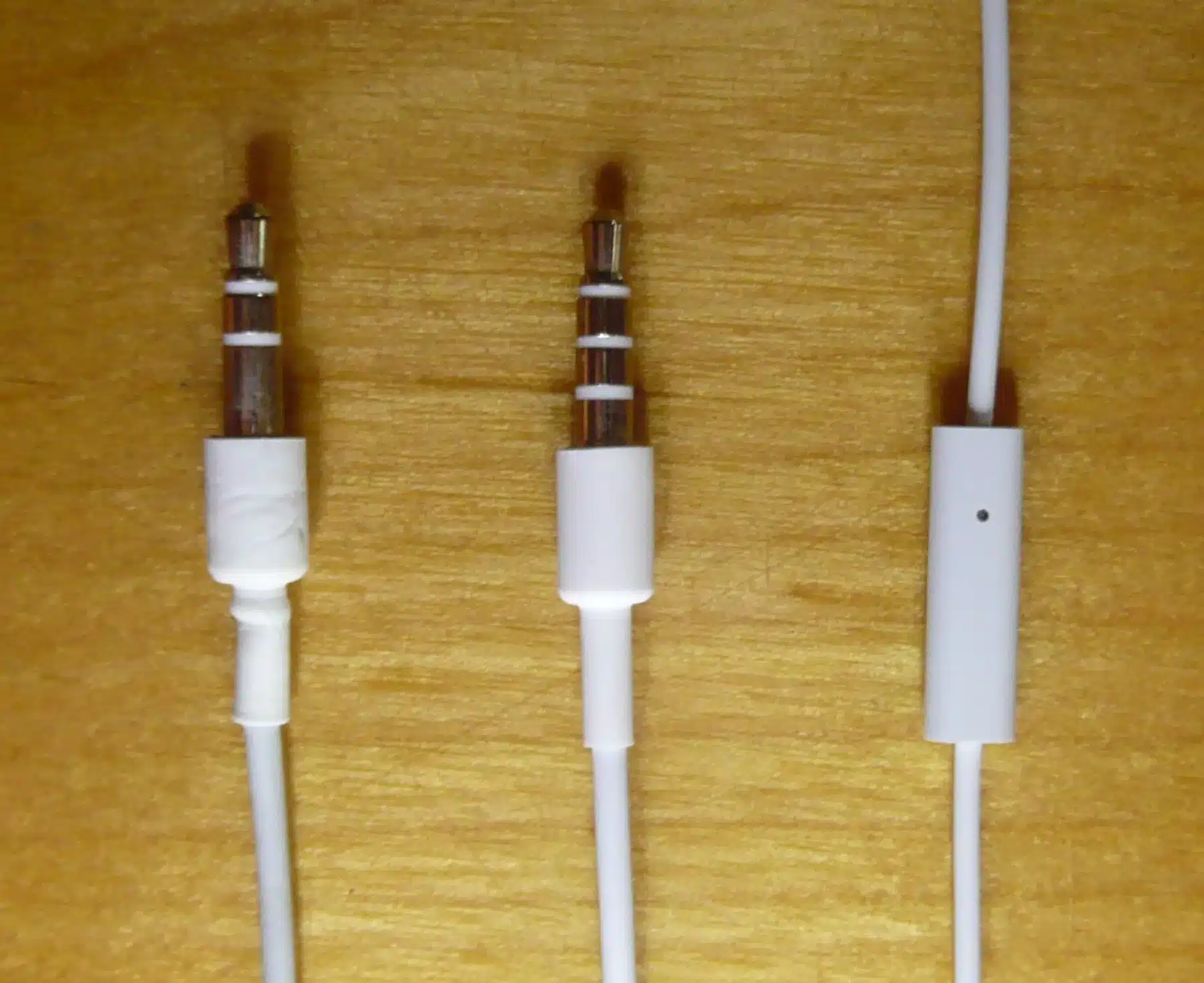 File:IPod and iPhone audio plugs.JPG - three white and brown cables on a wooden surface