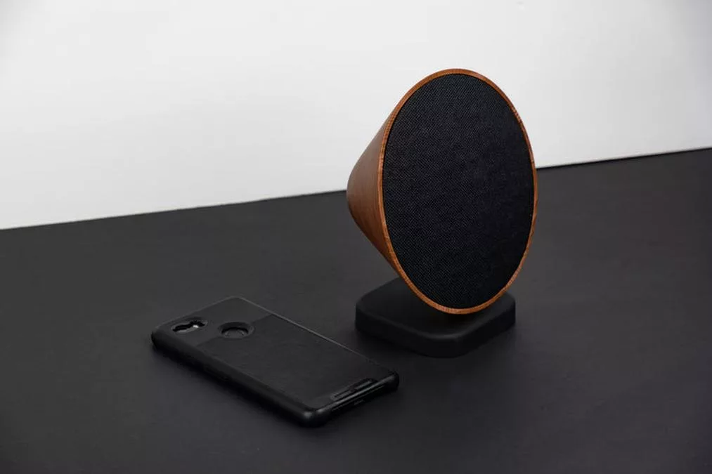 mobile phone and walnut speaker - a black phone and a wooden stand